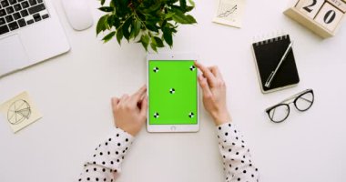 Üstten Görünüm Ofis Masası ve yeşil ekran ve eller üzerinde kayıt olan beyaz tablet bilgisayar. Dikey. Yanında başı işleri. Chroma anahtar. Hareket izleme