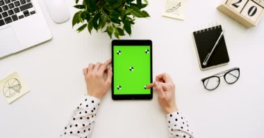 Üstten Görünüm Ofis Masası ve yeşil ekran ve eller üzerinde kayıt olan siyah tablet bilgisayar. Dikey. Yanında başı işleri. Chroma anahtar. Hareket izleme