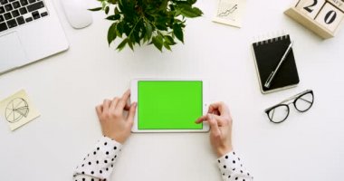 Üstten Görünüm Ofis Masası ve yeşil ekran ve eller üzerinde kayıt olan beyaz tablet bilgisayar. Yatay. Yanında başı işleri. Chroma anahtar.