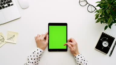 Üstten Görünüm Ofis Masası ve yeşil ekran ve eller üzerinde kayıt olan siyah tablet bilgisayar. Dikey. Yanında başı işleri. Chroma anahtar.