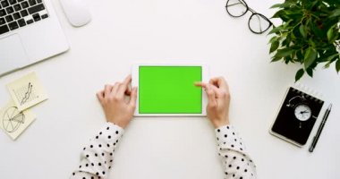Üstten Görünüm Ofis Masası ve yeşil ekran ve eller üzerinde kayıt olan beyaz tablet bilgisayar. Dikey. Yanında başı işleri. Chroma anahtar.