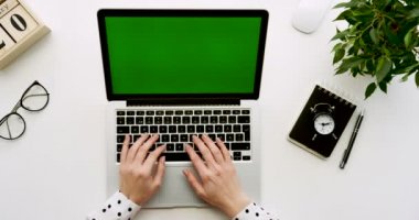 Üstten Görünüm ofis masaları olan dizüstü bilgisayar ile yeşil ekran ve üzerinde taping eller üzerinde. Notebooklar yanında. Chroma anahtar.