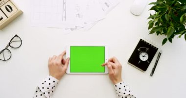 Üstten Görünüm Ofis Masası ve yeşil ekran ve eller üzerinde kayıt olan beyaz tablet bilgisayar. Yatay. Yanında başı işleri. Chroma anahtar.