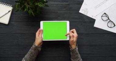 Üstten Görünüm siyah Ofis Masası ve yeşil ekran ve eller üzerinde kayıt olan beyaz tablet bilgisayar. Yatay. Yanında başı işleri. Chroma anahtar.