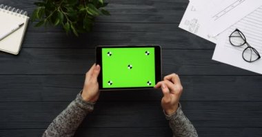 Üstten Görünüm siyah Ofis Masası ve yeşil ekran ve eller üzerinde kayıt olan siyah tablet bilgisayar. Yatay. Yanında başı işleri. Chroma anahtar. Hareket izleme