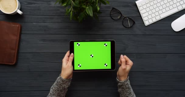Widok z góry na czarne biurko i komputer typu tablet czarny z zielonym ekranem i kobiecych rąk taping na nim. Poziomej. Biuro rzeczy obok. Kluczowanie. Śledzenie ruchu — Wideo stockowe