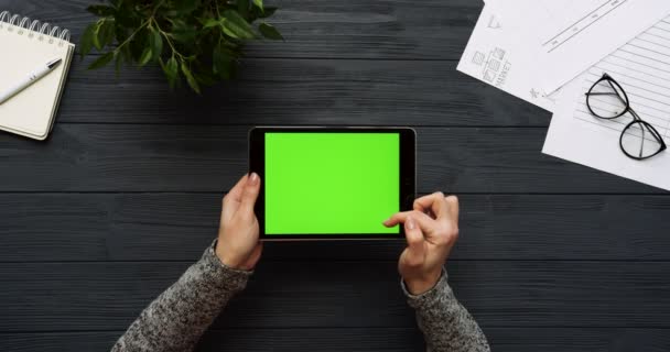 Vista dall'alto sulla scrivania dell'ufficio nero e computer tablet nero con schermo verde e le mani femminili su di esso. Orizzontale. Roba da ufficio. Chiave cromatica . — Video Stock