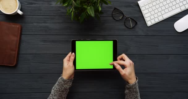 Vista dall'alto sulla scrivania dell'ufficio nero e computer tablet nero con schermo verde e le mani femminili su di esso. Orizzontale. Roba da ufficio. Chiave cromatica . — Video Stock