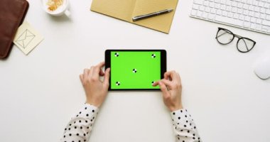 Üstten Görünüm beyaz Ofis Masası ve yeşil ekran ve eller üzerinde kayıt olan siyah tablet bilgisayar. Yatay. Yanında başı işleri. Chroma anahtar. Hareket izleme