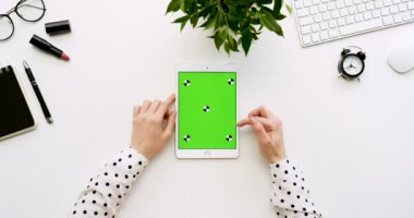 Üstten Görünüm beyaz Ofis Masası ve yeşil ekran ve eller üzerinde kayıt olan beyaz tablet bilgisayar. Dikey. Yanında başı işleri. Chroma anahtar. Hareket izleme