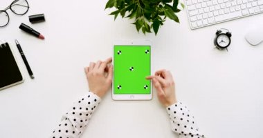 Üstten Görünüm beyaz Ofis Masası ve yeşil ekran ve eller üzerinde kayıt olan beyaz tablet bilgisayar. Dikey. Yanında başı işleri. Chroma anahtar. Hareket izleme