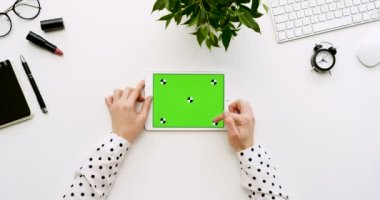 Üstten Görünüm beyaz Ofis Masası ve yeşil ekran ve eller üzerinde kayıt olan beyaz tablet bilgisayar. Yatay. Yanında başı işleri. Chroma anahtar. Hareket izleme