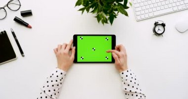 Üstten Görünüm beyaz Ofis Masası ve yeşil ekran ve eller üzerinde kayıt olan siyah tablet bilgisayar. Yatay. Yanında başı işleri. Chroma anahtar. Hareket izleme