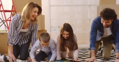 Mutlu aile anne ve iki çocuk paked arasında oturma odasında halı untwisting ne zaman onlar yeni evinde taşıma kutuları. Kapalı