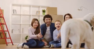 Mutlu dostu aile açmak kutuları arasında katta oturan ve Yeni dairende hareketli çünkü mutlu görünüyordu ederken şirin bir labrador köpek yavrusu ile oynuyor. Kapalı