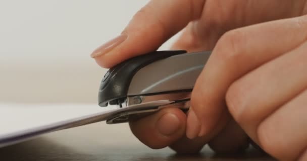 Macro shooting of the female hand doing holes in the papers by stepler. Close up — Stock Video