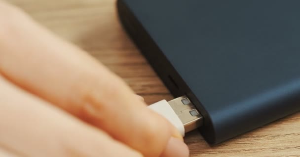 Macro of the black hard drive on the table and female hand putting a white cable in it. Close up — Stock Video