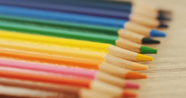 Närbild av färgglada pennor liggandes på skrivbordet i raden och en att ta bort. Makro. Ovanifrån — Stockvideo