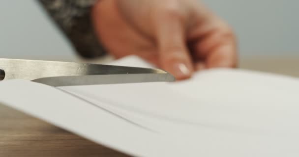 Cierre de la mano de las mujeres sosteniendo tijeras y cortando una hoja de papel blanco. Macro — Vídeo de stock