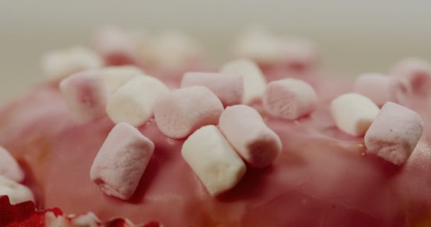 Macro de la rosquilla rosa con malvaviscos en la parte superior de la misma. De cerca. — Vídeo de stock