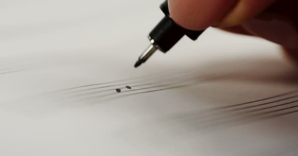 Крупним планом жіноча рука пише нотатки з ручкою в музичному записнику. Макро — стокове відео