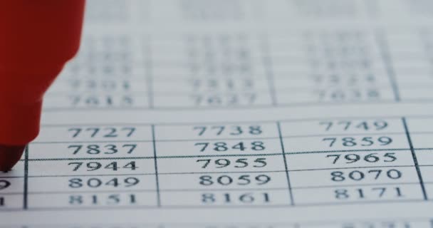 Close up van de grafiek met nummers liggen op de tafel en een pen of een marker een rode streep op de rij met een rode kleur. Macro — Stockvideo