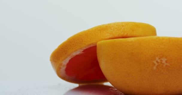 Макро вырезанного грейпфрута с капельками воды на катящемся перед камерой на белом фоне. Закрыть — стоковое видео