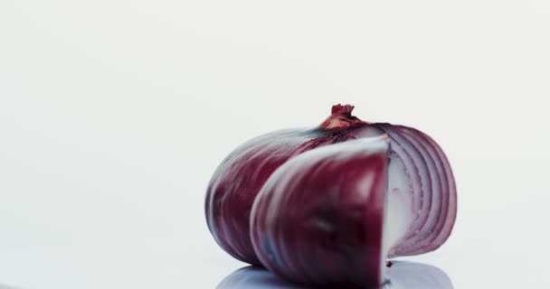 Makroaufnahme der beiden Zwiebelhälften, die auf dem weißen Wandhintergrund rollen. Nahaufnahme — Stockvideo