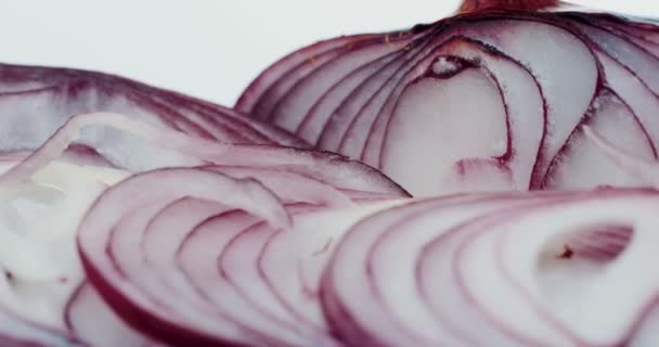 Macro de la cebolla morada cortada rodando delante de la cámara sobre el fondo blanco. De cerca. — Vídeo de stock