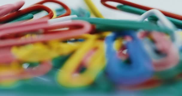 Macro shooting of the colourful paper clips. Focus zooming in. On the white background. Close up — Stock Video