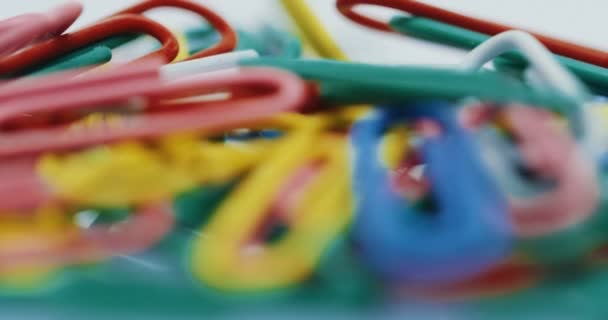 Macro-opnamen van de kleurrijke paperclips. Focus door in te zoomen. Op de witte achtergrond. Close-up — Stockvideo