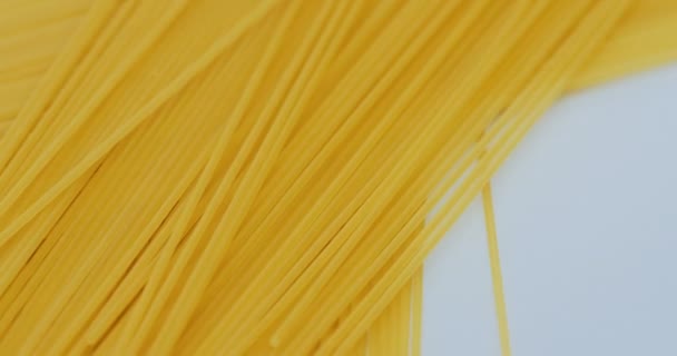 Bovenaanzicht op de glooiende spaghetti liggend op de witte achtergrond. Macro-opnamen — Stockvideo