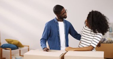 Neşeli Afrika kökenli Amerikalı portre çekim sadece çift ayakta yakınındaki kutuları oturma odasında birbirine bakarak, kamera önünde sarılma ve anahtar taşı--dan onların yeni düz gösteren, evli