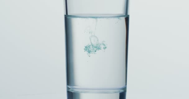 Close up van de groene verf druppels vallen in het glas met water. Macro schot — Stockvideo