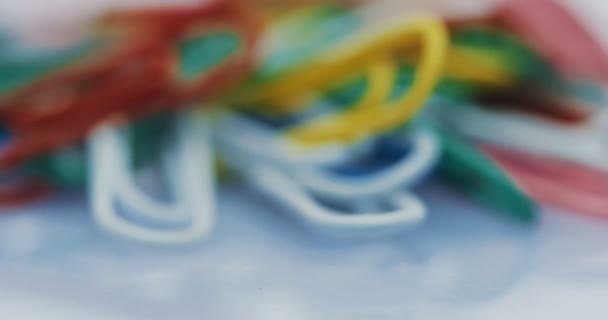 Macro of the colourful paper clips spinning in front of the camera on the white background. Blurred. Close up — Stock Video