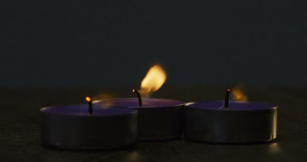 Gros plan des bougies qui brûlent et qui s'éteignent devant la caméra dans l'obscurité. Prise de vue macro — Video