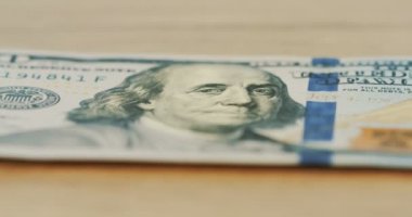 Ahşap masanın üzerinde yatan 100 dolar bill devam odak. Makro. Yakın çekim