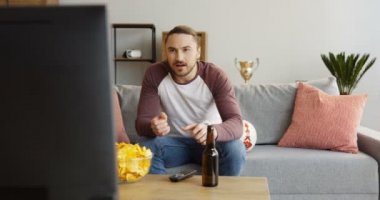 Evde spor oyun TV izlerken neşelenmeye beyaz adam portre vurdu. Bira ve cips. Kapalı