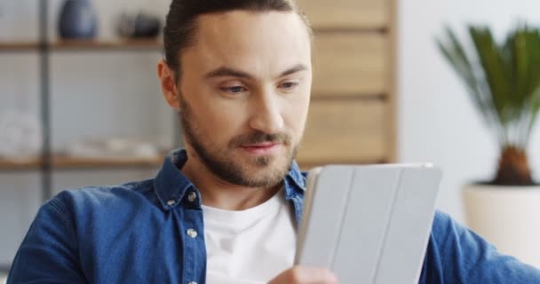 Primo piano del giovane uomo attraente che usa il computer di targa. A casa. Ritratto. Interni — Video Stock