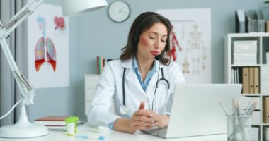Kafkasyalı genç kadın doktor portresi hastayla çevrimiçi video kaset aracılığıyla konuşuyor ve kameraya gülümsüyor. Kadın doktor internet danışmanlığı yapıyor..