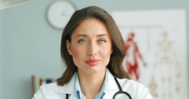 Beyaz cüppeli ve steteskoplu beyaz kadın hekimin sıcak dolabında kameraya gülümseyen yüzünü kapatın. Mutlu kadın doktor gülüşünün portresi. Sağlık hizmetleri kavramı