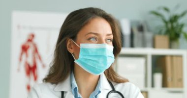 Mavi tıbbi maskeli, yüzü kameraya dönük, beyaz, güzel bir kadın doktora yaklaş. Koronavirüsten korunan güzel bir kadın doktorun portresi..