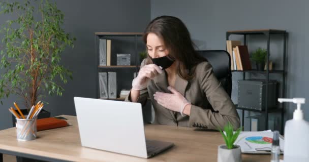 Joven mujer de negocios caucásica enferma en máscara y guantes de goma escribiendo en el teclado y trabajando en el ordenador portátil. Trabajadora de oficina cansada malsana que se ríe y estira el cuello. Coronavirus . — Vídeo de stock