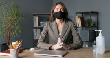 Maskeli genç ve güzel bir iş blogcusu ofisinde oturmuş kamerayla konuşuyor. İş kadını iş ve öğretim elemanı. Kadın karantinada blog yazıyor..