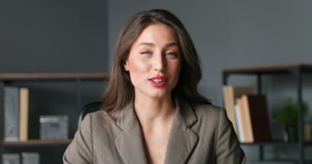 Primer plano de la hermosa bloguera joven hablando con la cámara en la oficina. Empresaria explicando y enseñando en línea. Mujer haciendo clases de blogueo sobre cuarentena y entrenamiento. Entrenador contar historia . — Vídeos de Stock