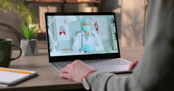 Κορίτσι μιλάει με το γιατρό σε βιντεοκλήση στο laptop και δείχνει ιατρική μάσκα και απολυμαντικό. Γιατρός με μάσκα που κάθεται στο ντουλάπι και παρέχει online συμβουλές και συμβουλές υγείας σε γυναίκα ασθενή. — Αρχείο Βίντεο
