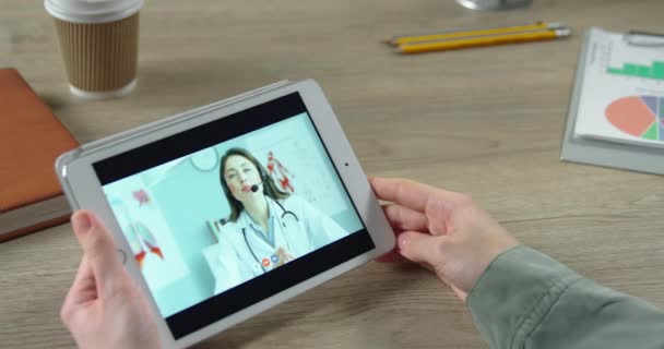 Mooie dokter in headset geeft gezondheidsadvies aan meisje in videoconferentie. Sluit het tabletscherm af met online overleg met de blanke vrouwelijke arts die de duim opgeeft. Gezondheidsconcept — Stockvideo