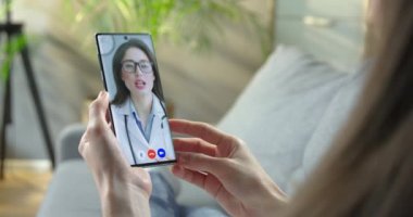 Güzel doktor, hastanede otururken akıllı telefondan bir kıza görüntülü konuşma tavsiyesi veriyor. Kadın, video konferansında beyaz kadın doktorla görüşüyor. Sağlık hizmetleri kavramı