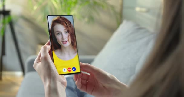 Mobiel scherm met videogesprek tussen twee meisjes. Vrouw met online video chat met mooie roodharige blanke meisje indoor. Vrouw videochatting op smartphone tijdens het rusten in de kamer. Beginbegrip — Stockvideo