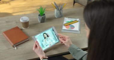 Tablet üzerindeki video konferansında güzel beyaz bir doktorla tıbbi görüşmeler yapan bir kız. Kulaklıklı kadın doktor, kadın tıbba görüntülü konuşma cihazını gösteriyor. Tedavi kavramı